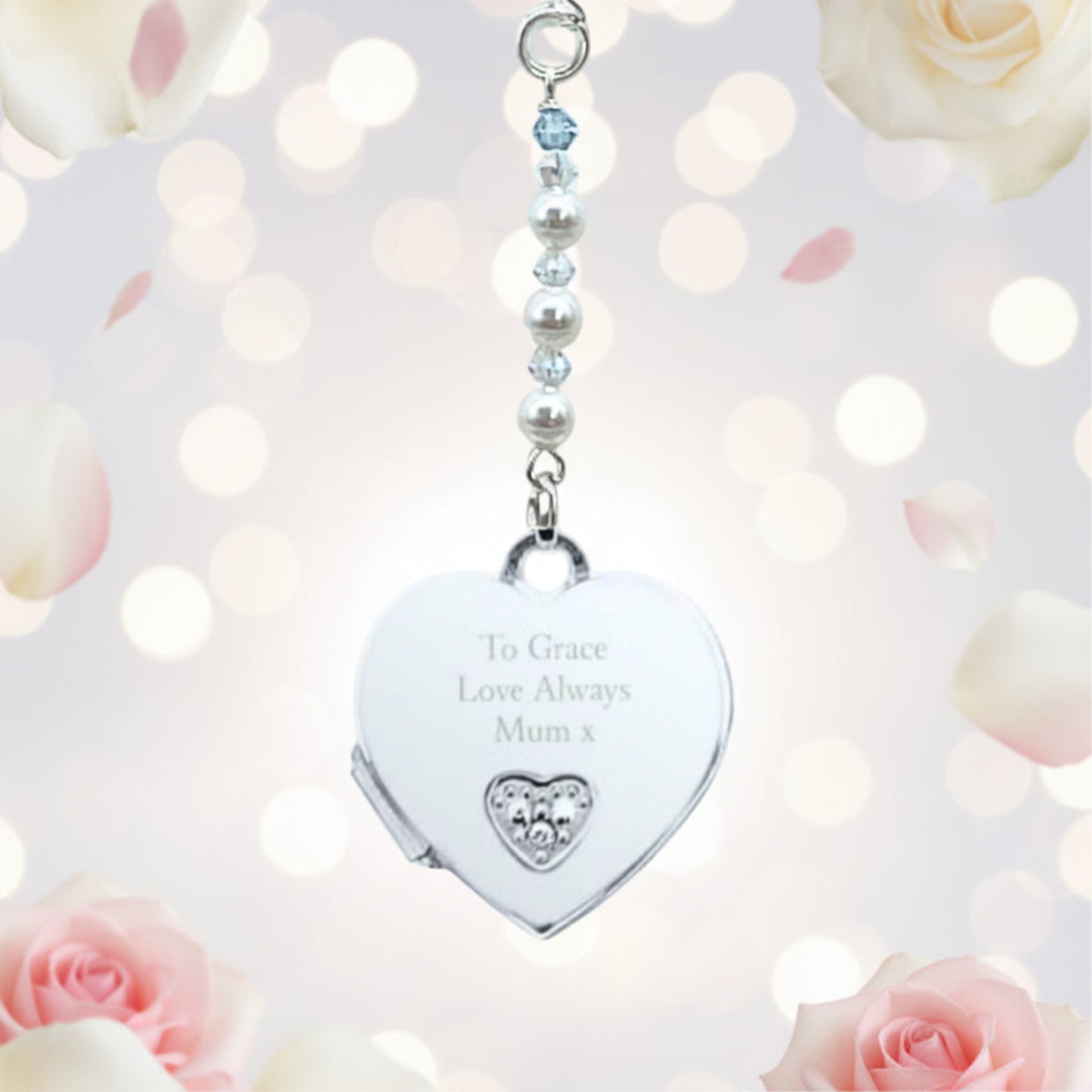 A sterling silver heart shaped locket wedding bouquet charm, engraved with wording of your choice on the front of the heart. The locket opens to add two photos of your choice. Suspended from a string of crystals and glass pearls with a tiny blue bead for your something blue.