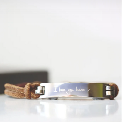 A brown leather bracelet with a central metal plate engraved with your own words and a silver lobster clasp