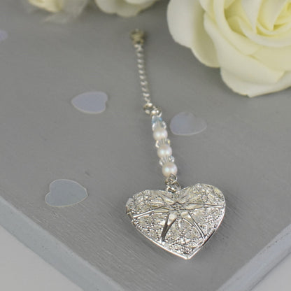 Heart shaped filigree locket opens to take one photo. Suspended from a line of glass pearls and Austrian crystals and finished with a tiny blue bead. The charm is suspended from a sterling silver chain and lobster clasp to fasten securely to a wedding bouquet.
