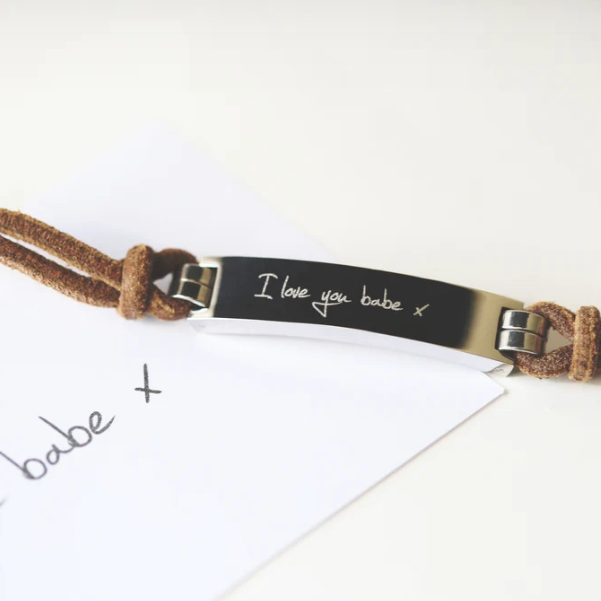 A brown leather bracelet with a central metal plate engraved with your own words and a silver lobster clasp