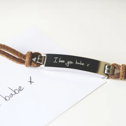 A brown leather bracelet with a central metal plate engraved with your own words and a silver lobster clasp