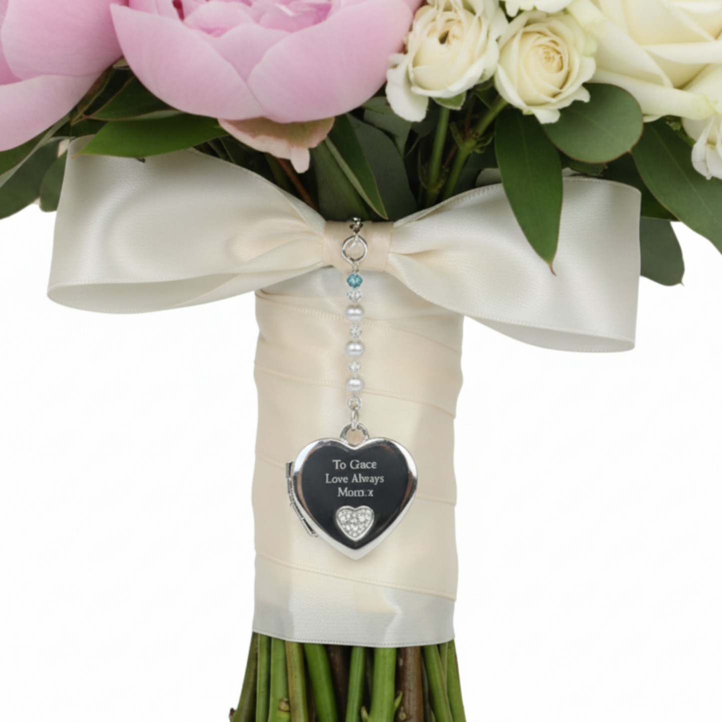 Sterling silver heart shaped locket wedding bouquet charm. Shown on wedding bouquet. Suspended from a string of crystals and glass pearls with a tiny something blue bead