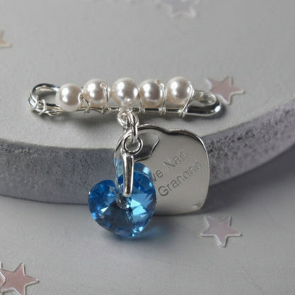 A sterling silver safety pin is finished with 4mm white glass pearls The loop on the pin hold a sterling silver bail with the highest quality blue crystal heart. Shown with an optional 19mm sterling silver heart engraved with your own words