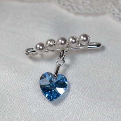 A sterling silver safety pin is finished with 4mm white glass pearls The loop on the pin hold a sterling silver bail with the highest quality blue crystal heart. The pin can be pinned to a wedding bouquet or worn inside the wedding gown as a secret something blue.