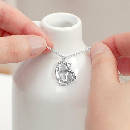 Personalised baby feet necklace. Engraved with baby’s name and date of birth on adjustable necklace. Shown in silver plate.