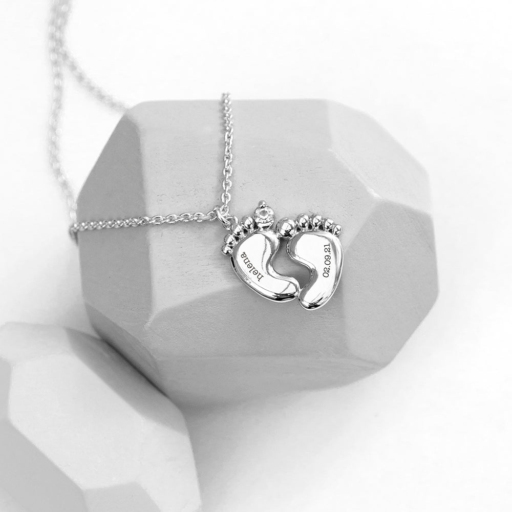 Personalised baby feet necklace. Engraved with baby’s name and date of birth on adjustable necklace. Shown in silver plate.