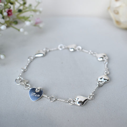 Sterling silver puffed hearts linked together by long twisted links. Next to the fastener is a small 10mm sterling silver heart engraved with a name of our choice.
