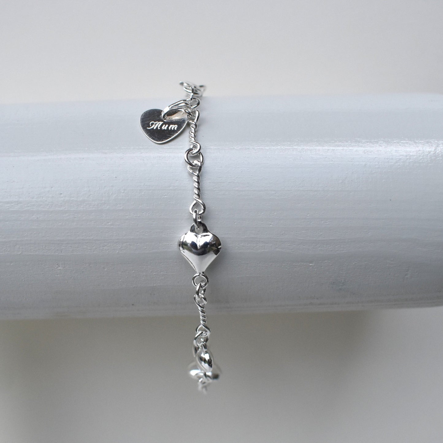 Sterling silver puffed heart and twist link bracelet showing a 10mm sterling silver heart engraved with the word "Mum". 