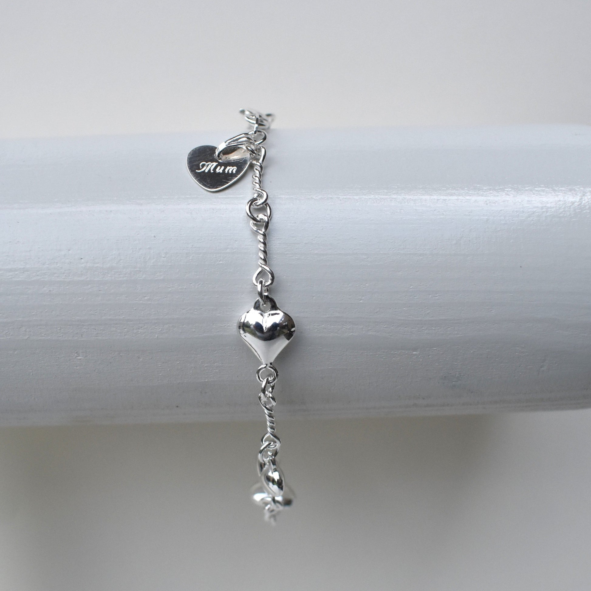 Sterling silver puffed heart and twist link bracelet showing a 10mm sterling silver heart engraved with the word "Mum". 