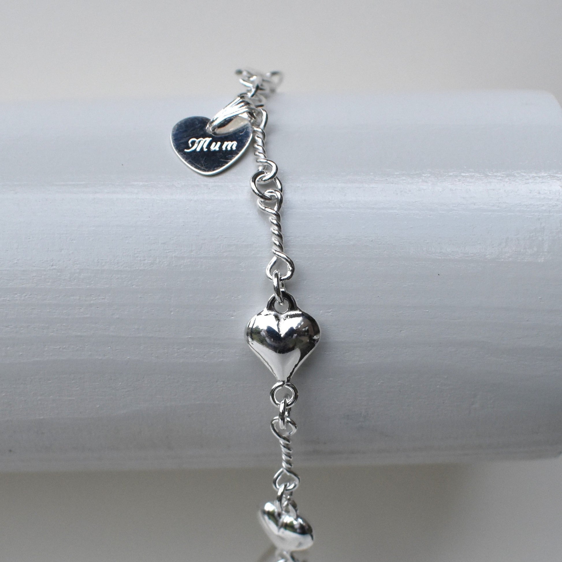 Sterling silver puffed hearts linked together by long twisted links. Next to the fastener is a small 10mm sterling silver heart engraved with a name of our choice.