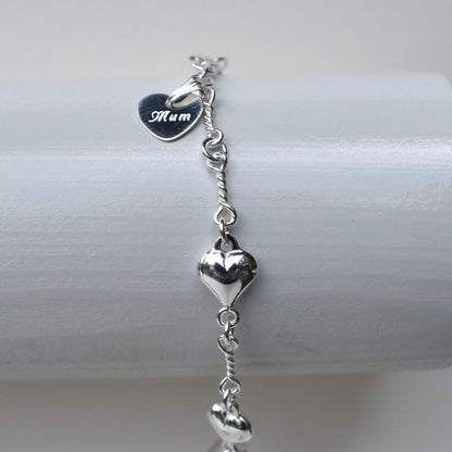 Sterling silver puffed hearts linked together by long twisted links. Next to the fastener is a small 10mm sterling silver heart engraved with a name of our choice.