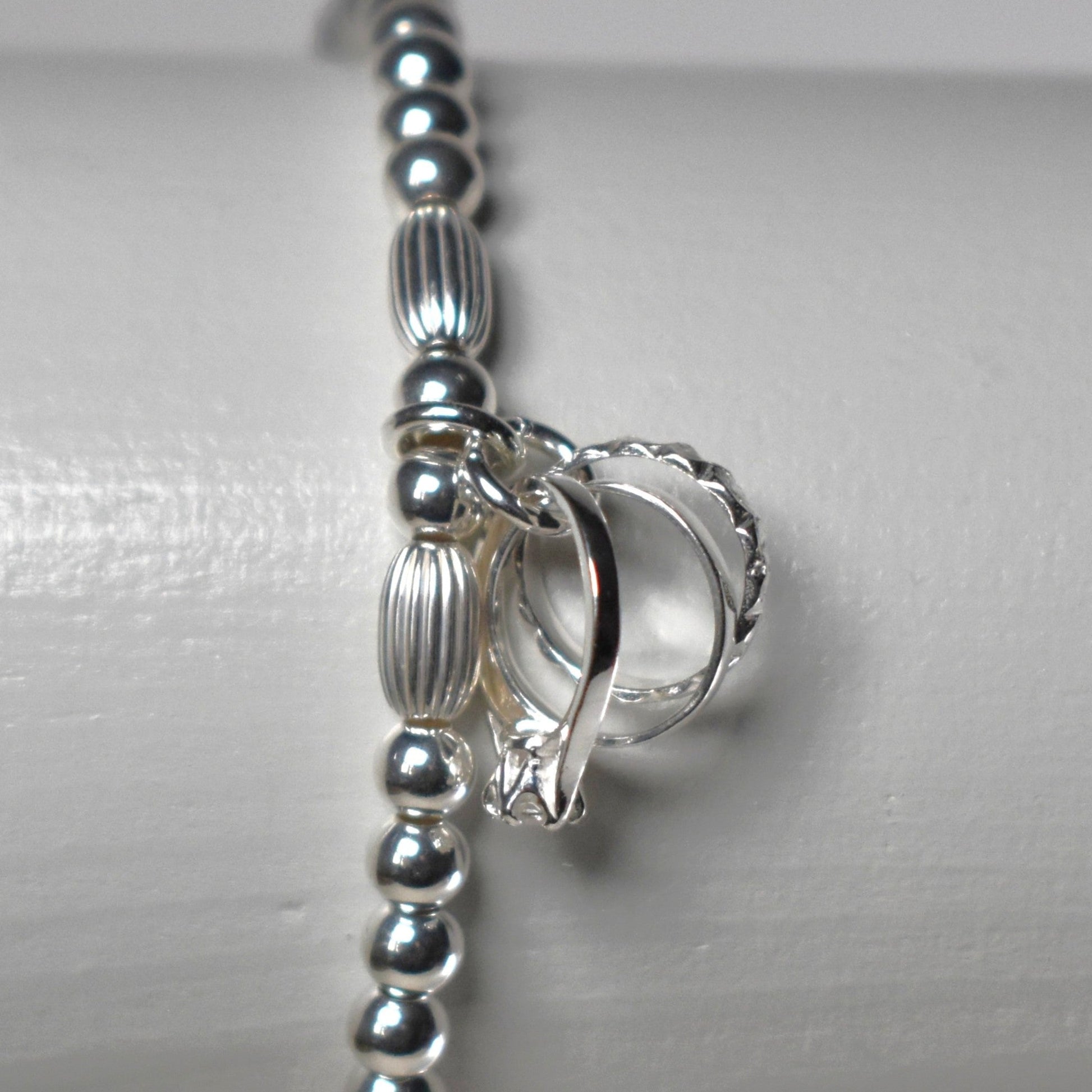 Sterling silver beads are threaded onto strong elastic and finished with a sterling silver charm symbolising engagement, wedding and eternity rings. 