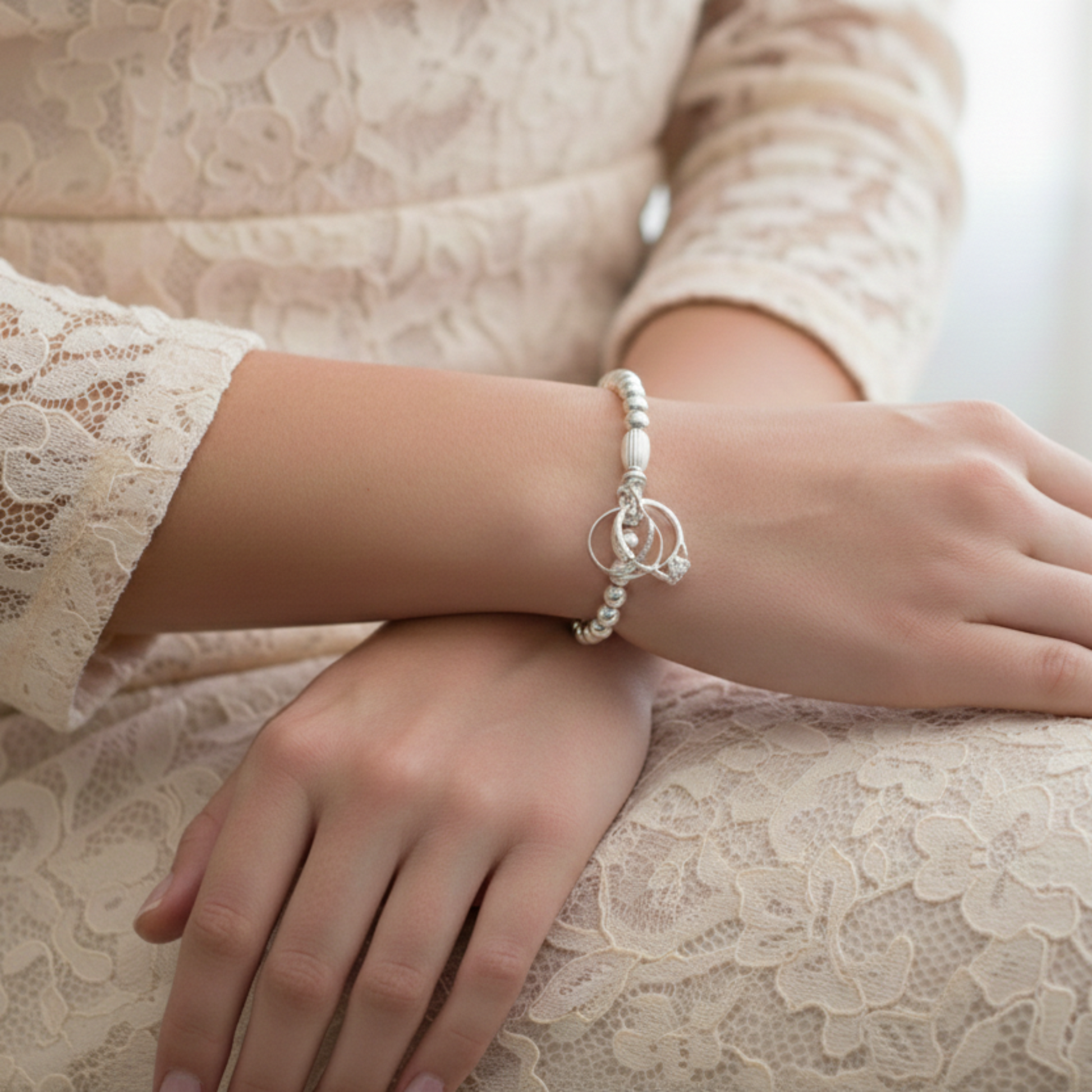 A sterling silver beaded stretch bracelet with a sterling silver charm representing engagement, wedding and eternity rings.