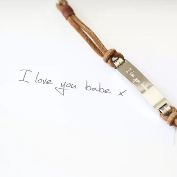 A brown leather bracelet with a central metal plate engraved with your own words and a silver lobster clasp