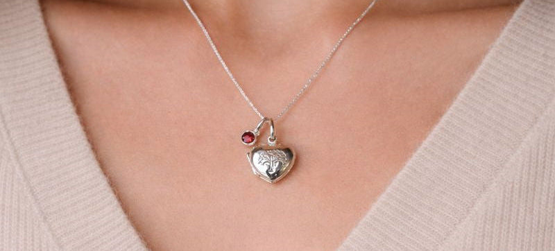 Sterling silver heart shaped locket with engraved family tree on the front. Opens to show space for two photos. Shown on an adjustable 16-18 inch sterling silver chain and with an optional birthstone. Shown worn