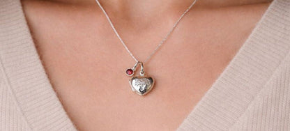 Sterling silver heart shaped locket with engraved family tree on the front. Opens to show space for two photos. Shown on an adjustable 16-18 inch sterling silver chain and with an optional birthstone. Shown worn