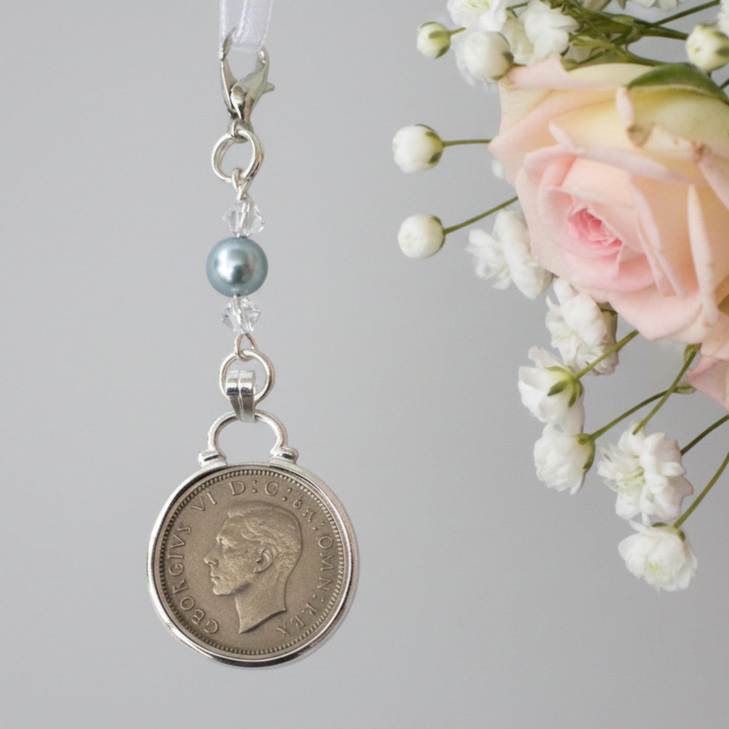 a real sixpence is securely mounted below a line of crystals with a blue bead. Finished with a lobster clasp and ribbon for you to add to your wedding bouquet
